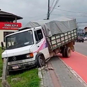 Motorista de caminhão perde a direção, sobe em calçada e colide contra cerca
