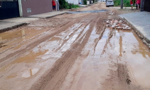 Moradores sofrem com buracos, poeira e lama deixados em rua após retirada de asfalto