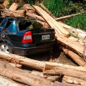 VÍDEO: Caminhão carregado de toras passa por cima de moto, carga atinge carro e mata motorista